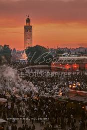 Image du Maroc Professionnelle de  Au coucher du soleil et même un peu avant la foule envahi la fameuse Place Jemaa El Fana qui se métamorphose en un gigantesque restaurant en plein air grâce aux nombreux stands et gargotes qui s'y installent sur ce lieu mythique au centre de la médina de Marrakech. Au fond le minaret de la Koutoubia, Samedi 26 Février 2005. (Photo / Abdeljalil Bounhar)

